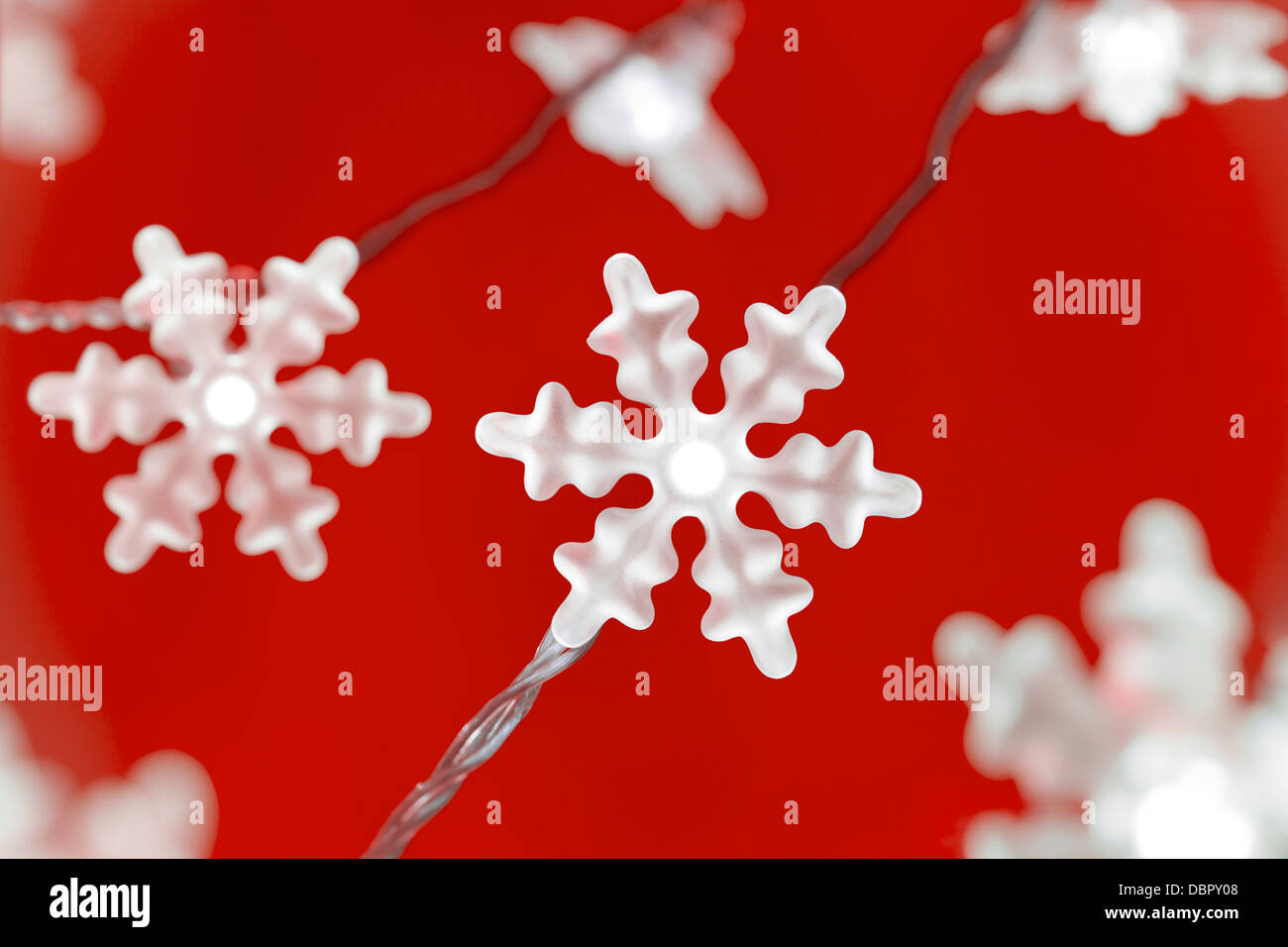 Schneeflocke geformte Lichterkette vor einem roten Hintergrund. Stockfoto
