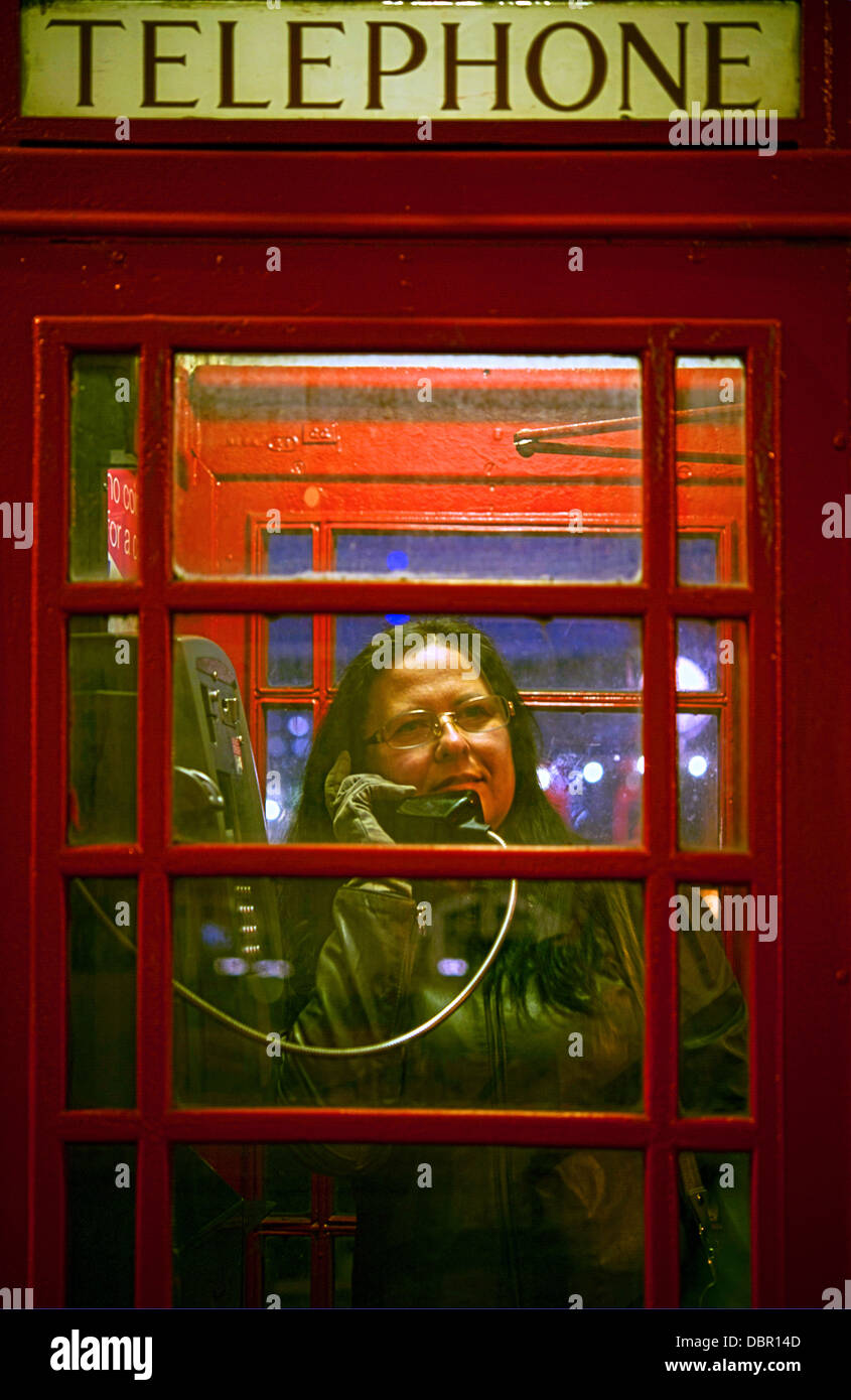 Frau am Telefon in einer Telefonzelle in London sprechen Stockfoto