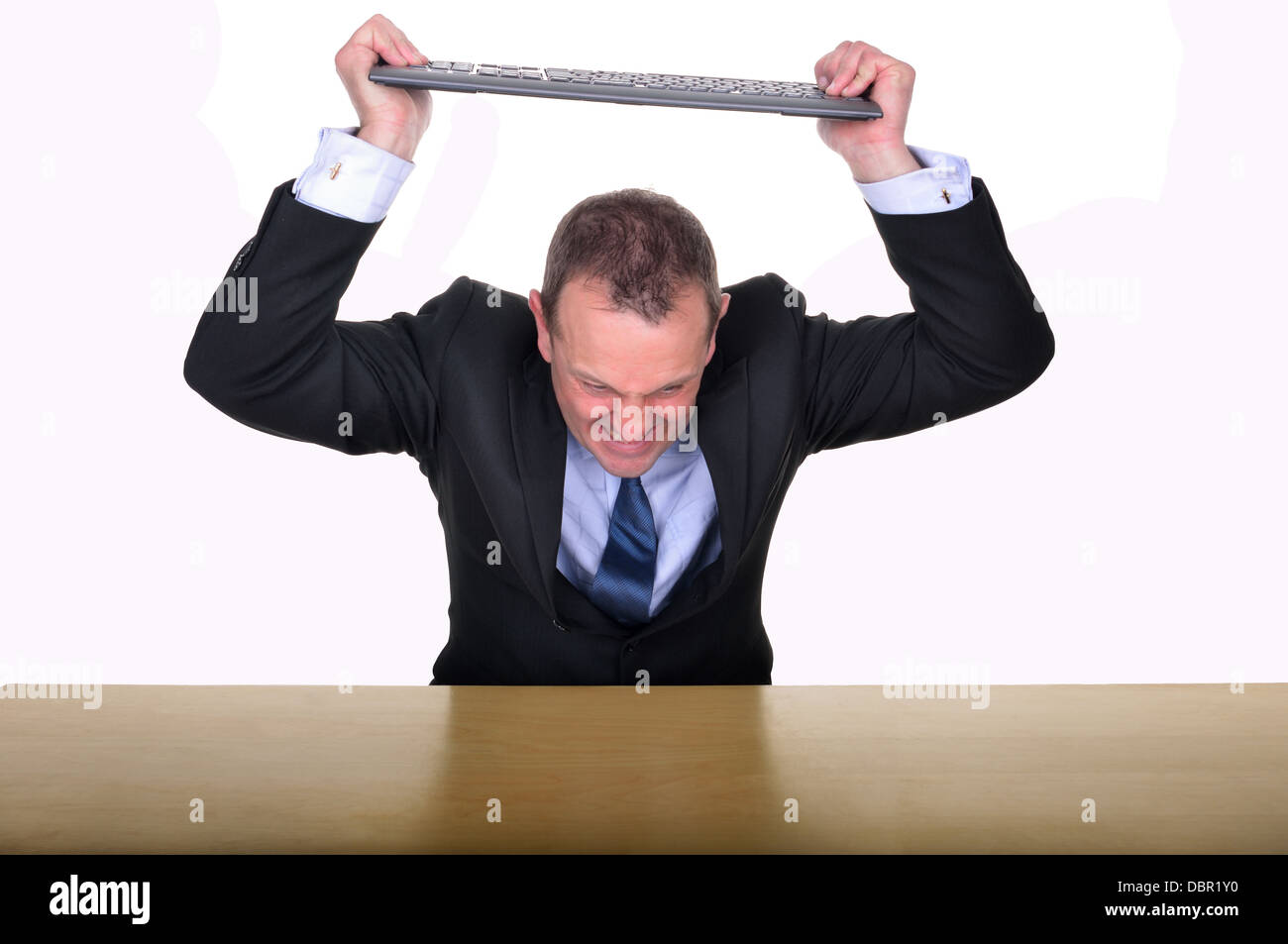Bild eines Unternehmers an einem Schreibtisch, eine Tastatur in der Frustration zu zerschlagen Stockfoto