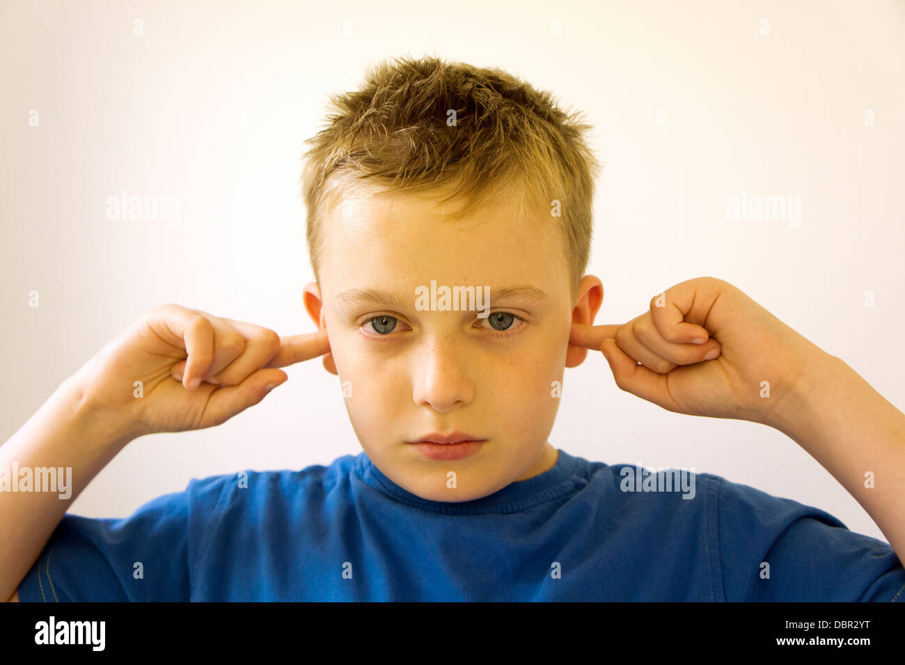 Junge stand mit seinen Fingern in den Ohren, die zeigen, dass er nicht zuhört Stockfoto