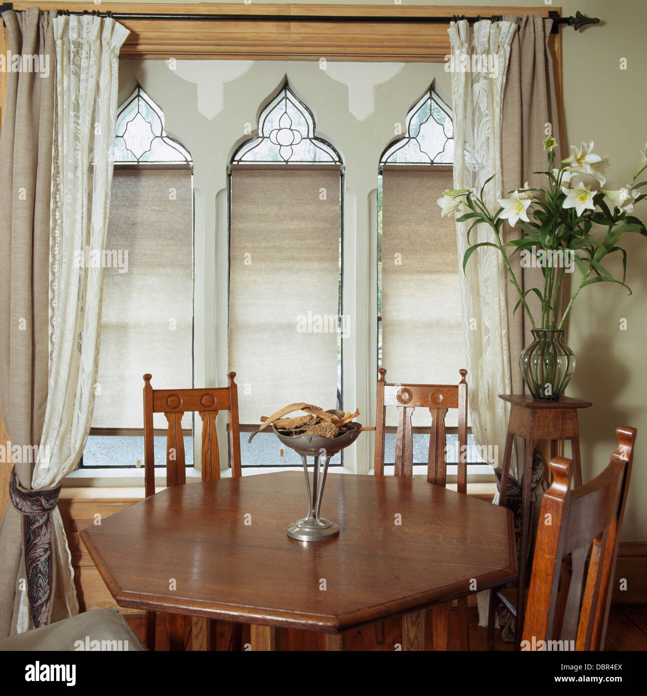 Kunst + Handwerk-Stil Stühle und Tisch im kleinen Speisesaal mit Beige-weiße Vorhänge auf gotische Fenster Stockfoto