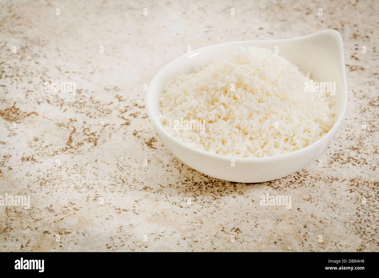 kleine Keramikschale Kokosflocken vor dem Hintergrund der keramischen Fliese mit einem Textfreiraum Stockfoto