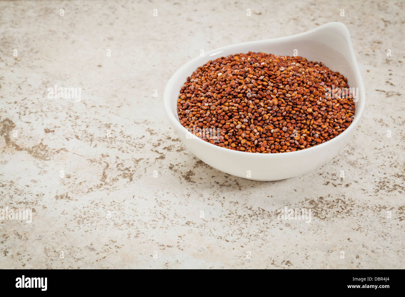 kleine Keramikschale rote Quinoa Getreide gegen eine keramische Fliese Hintergrund mit einem Textfreiraum Stockfoto