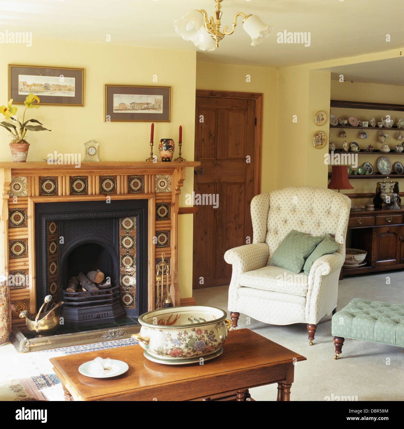 Cremefarbene Sessel am Kamin mit gefliesten Kaminsims im Ferienhaus  Wohnzimmer mit Couchtisch Kiefer Stockfotografie - Alamy