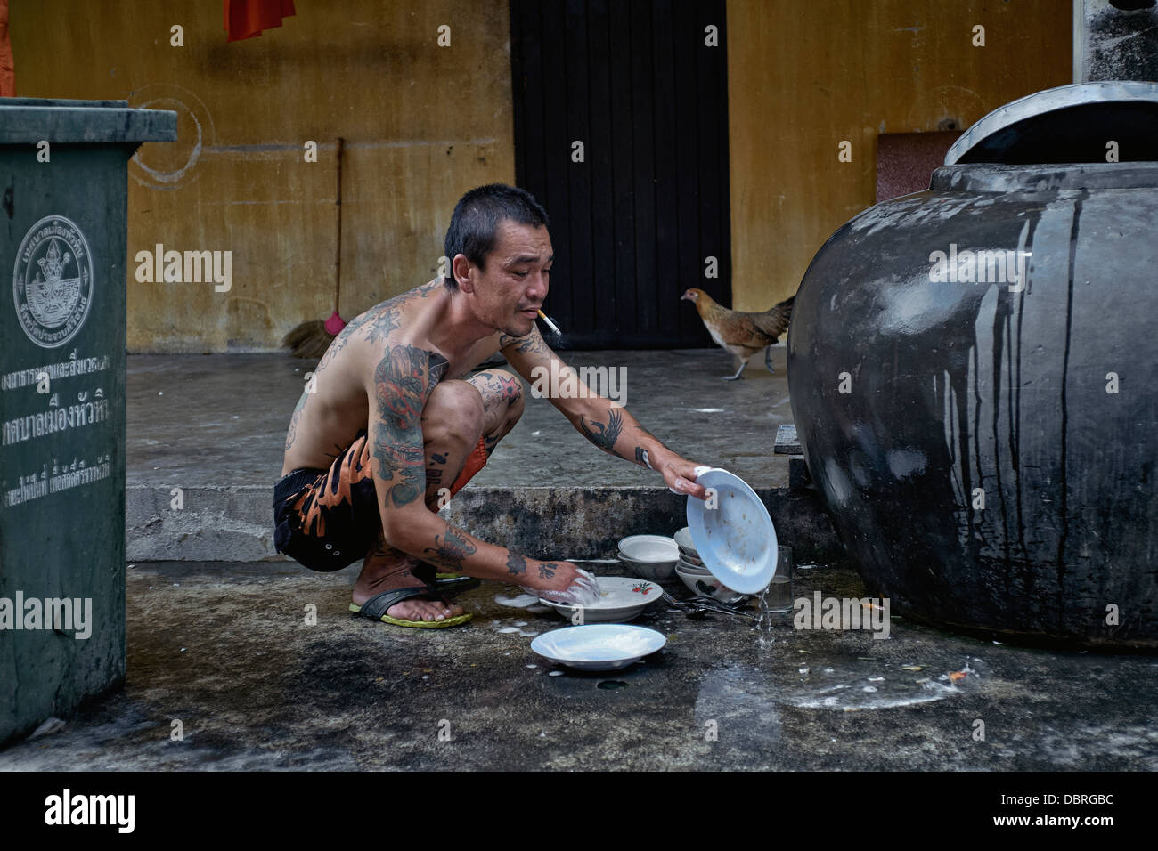 Mann abwaschen außerhalb. Thailand-Straßenszene. S. E. Asien Stockfoto