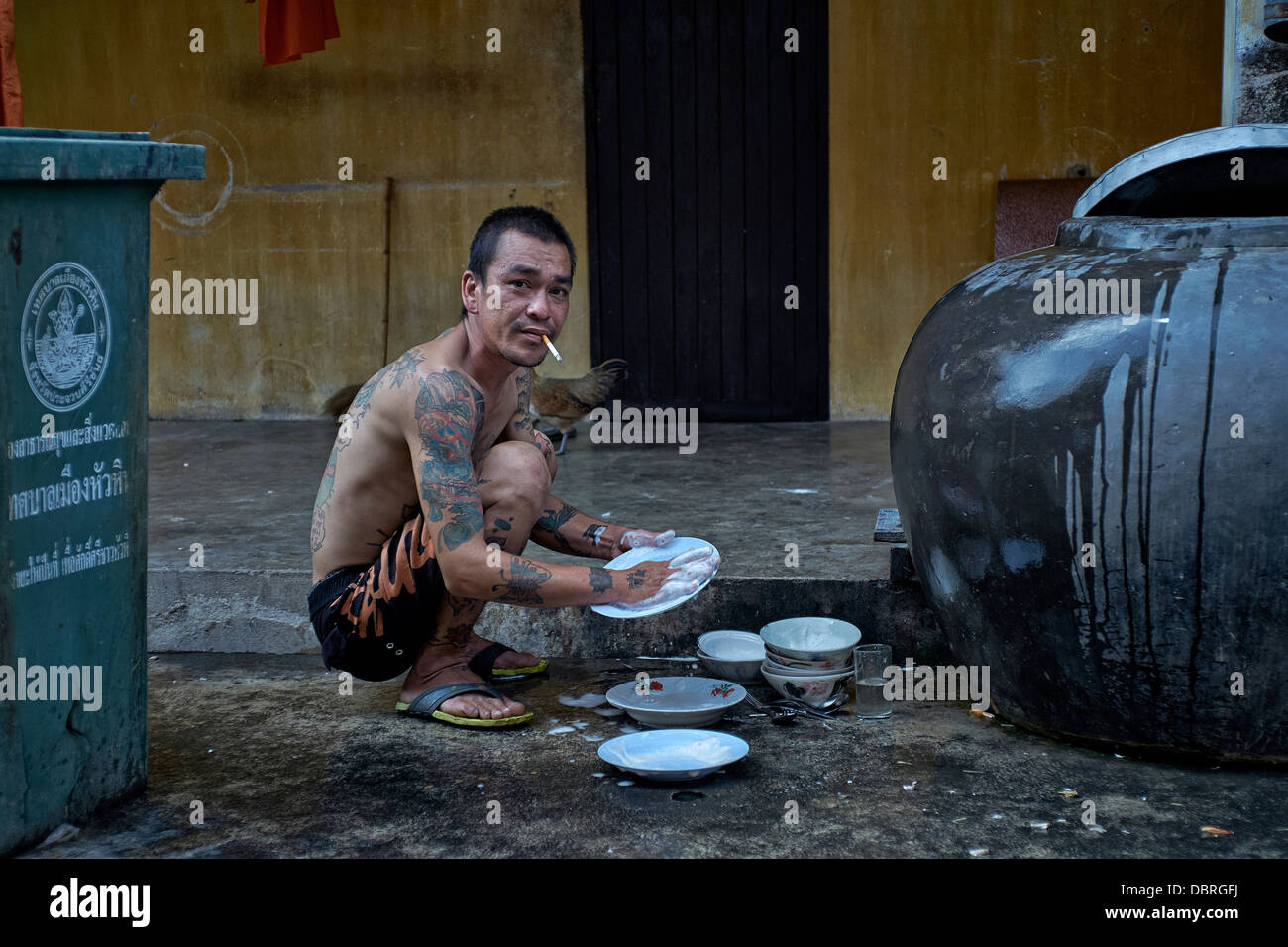 Mann abwaschen außerhalb. Thailand-Straßenszene. S. E. Asien Stockfoto