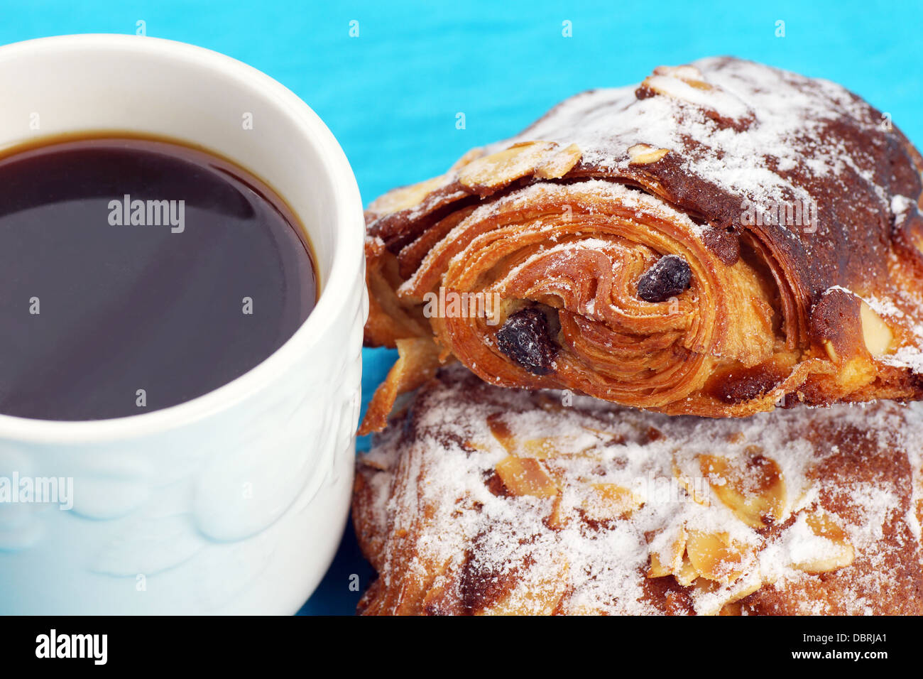 Köstliche Schokolade und Mandel Croissant mit schwarzen Kaffee über blau Stockfoto