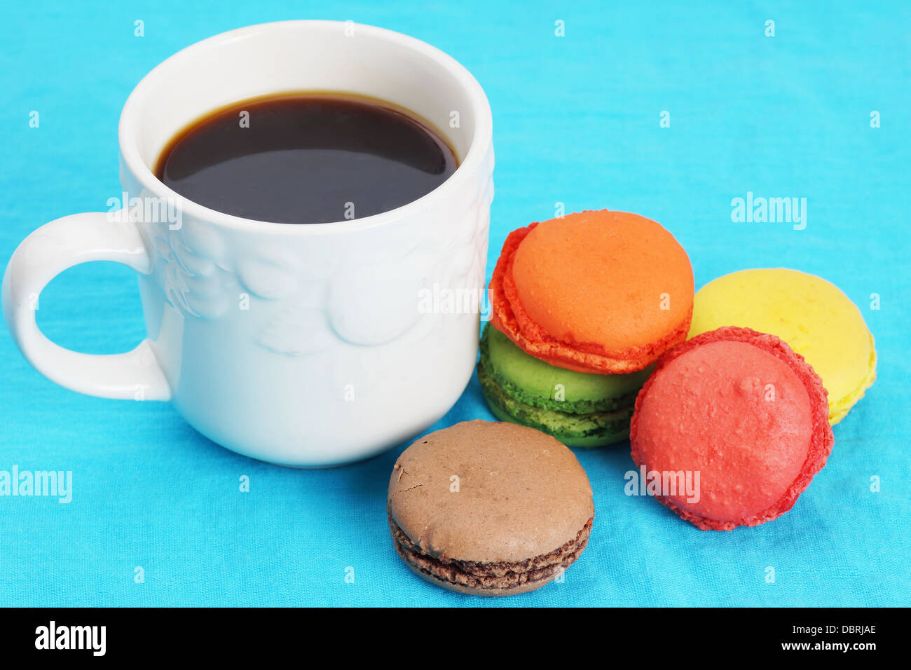 Tasse schwarzen Kaffee und bunten Macarons auf blau Stockfoto