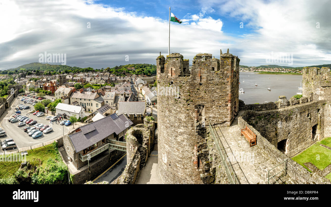 CONWY, Wales – Ein Panoramablick von den Stadtmauern von Conwy Castle, einer mittelalterlichen Festung aus dem 13. Jahrhundert in Nordwales, Großbritannien. Die Szene umfasst einige der imposanten Türme der Burg im Vordergrund, wobei die historische Stadt Conwy und der gewundene Fluss Conwy in der Ferne sichtbar sind. Dieses UNESCO-Weltkulturerbe, erbaut von König Eduard I., bietet einen beeindruckenden Blick auf die umliegende Landschaft und zeigt die strategische Bedeutung seiner Lage. Stockfoto