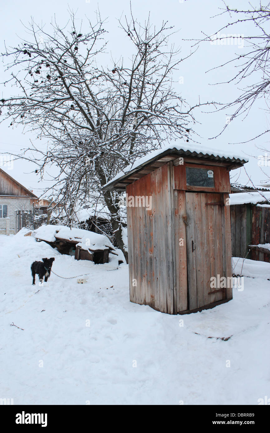 Ländliche Toilette und schwarzer Hund im winter Stockfoto