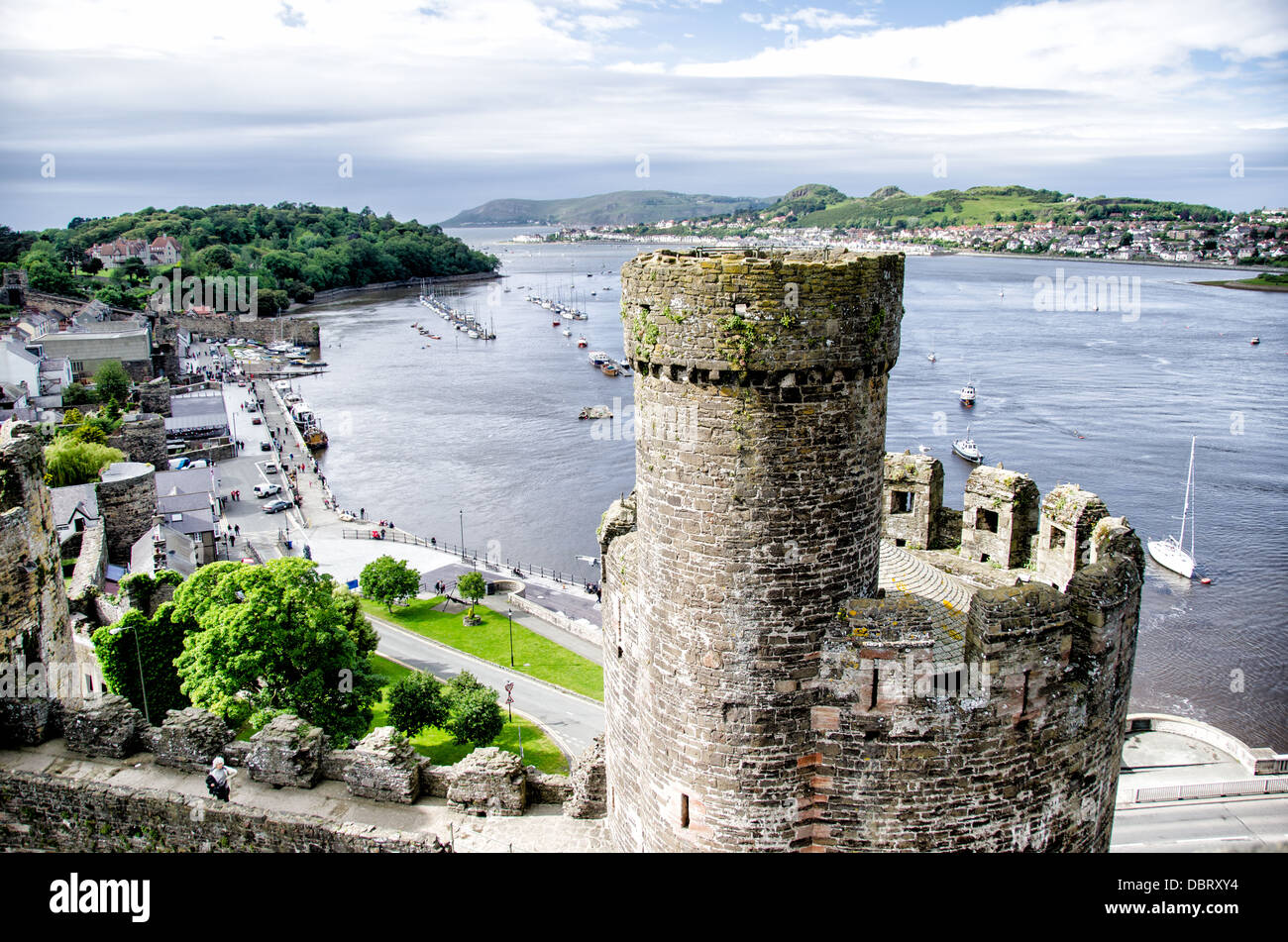 CONWY, Wales – Ein Blick auf den Fluss Conwy und die umliegende Landschaft, von den Türmen von Conwy Castle, einer mittelalterlichen Festung aus dem 13. Jahrhundert in Nordwales. Im Vordergrund befinden sich einige der gut erhaltenen Stadtmauern und Türme der Burg, die die beeindruckende Verteidigungsarchitektur dieses UNESCO-Weltkulturerbes hervorheben. Conwy Castle wurde von König Eduard I. während seiner Eroberung von Wales erbaut und bietet Besuchern einen Panoramablick auf die Stadt und die Mündung darunter. Stockfoto