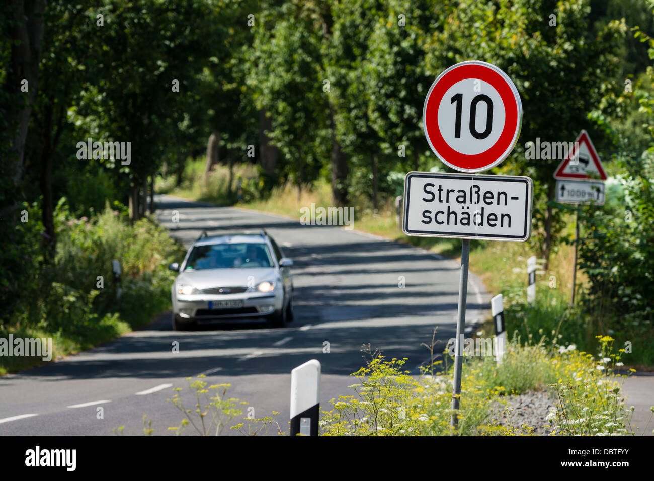 Ein Auto fährt auf der L657 Straße zwischen Dortmund-Mengede und Castrop-Rauxel. An Fahrbahn Schaden liegt die Höchstgeschwindigkeit 10 km/h Stockfoto