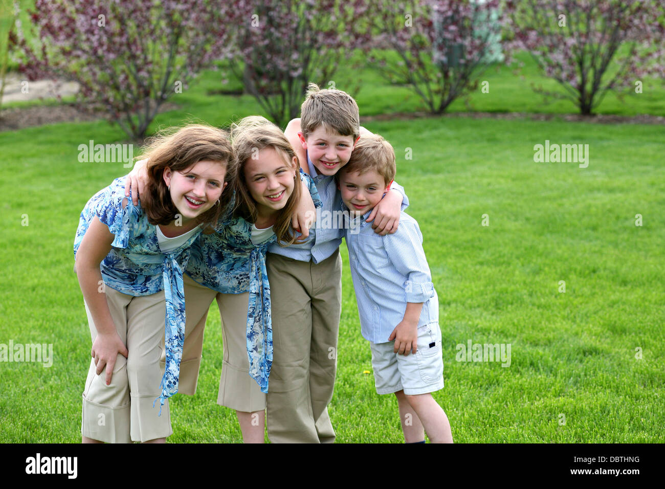 Schwestern und Brüder draußen im Hof lächelnd Stockfoto