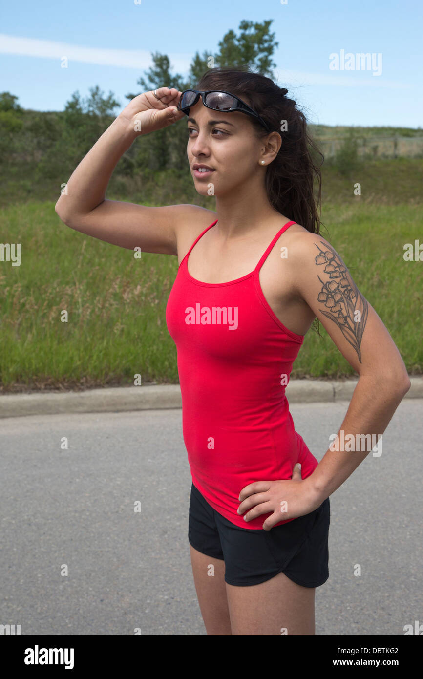 Fit Frau mit einem floralen Tattoo bereit für einen Lauf Blick auf eine Stadt Straße gehen Stockfoto