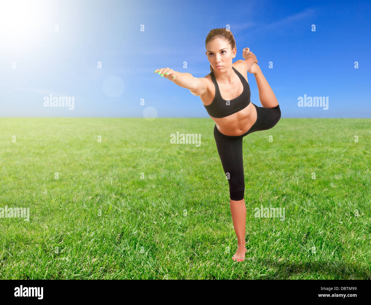 Frau, die Tänzerin Yoga machen posieren in einer Wiese mit einem Blendenfleck Stockfoto