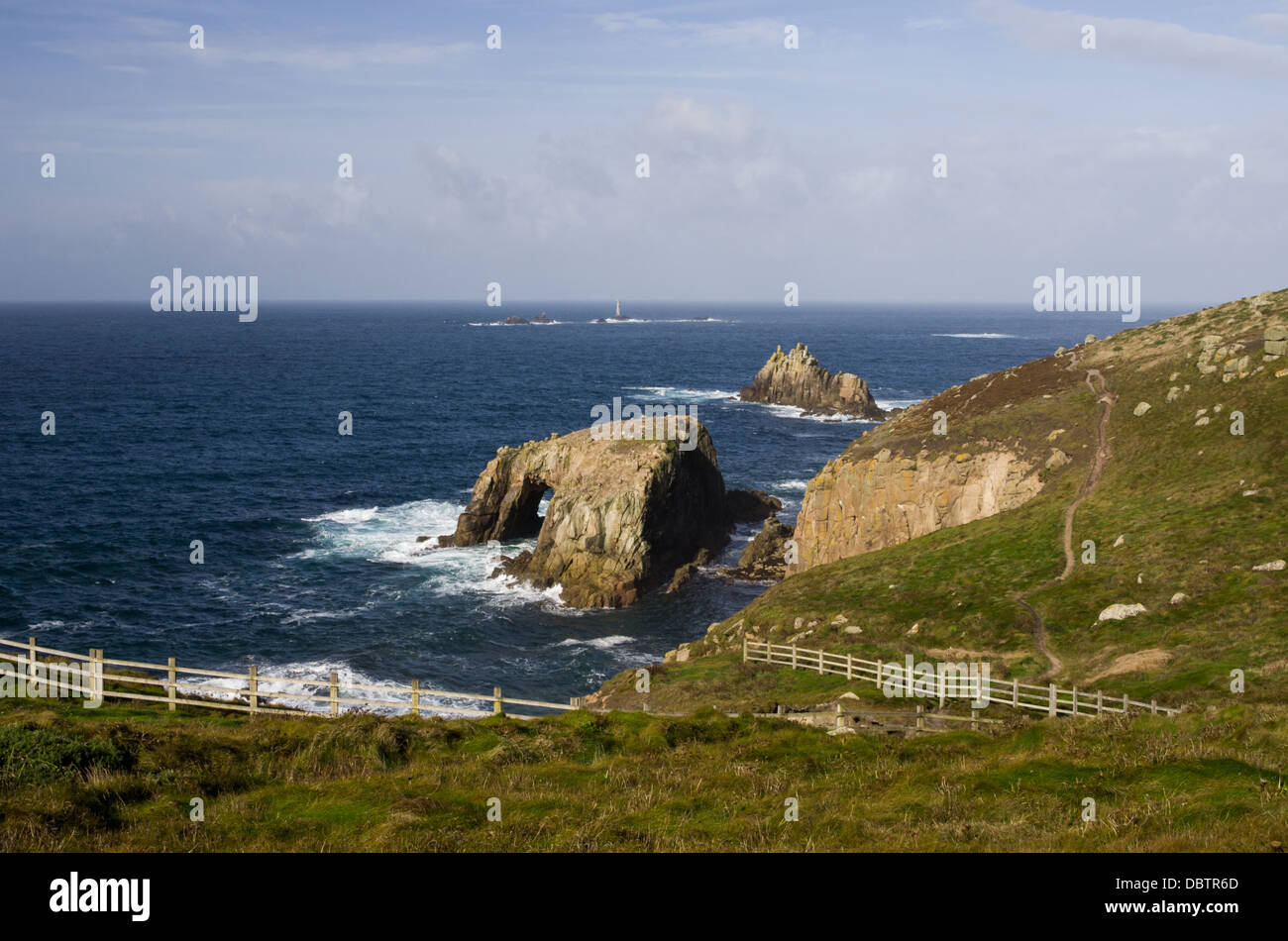 Ein Meer Szene in der Nähe von Endland mit Fußweg entlang der Küste und felsigen Inseln und ein Leuchtturm in der Ferne. Sonniger Tag. Stockfoto