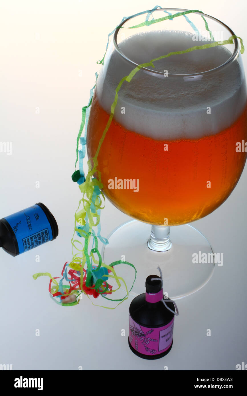 Glas Bier mit Party Poppers und Luftschlangen Stockfoto