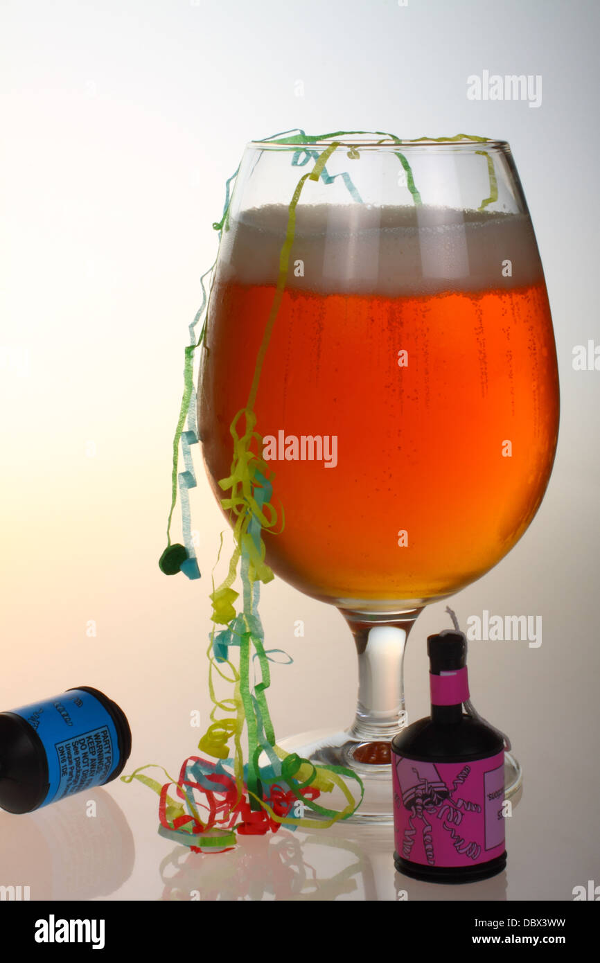 Glas Bier mit Party Poppers und Luftschlangen Stockfoto