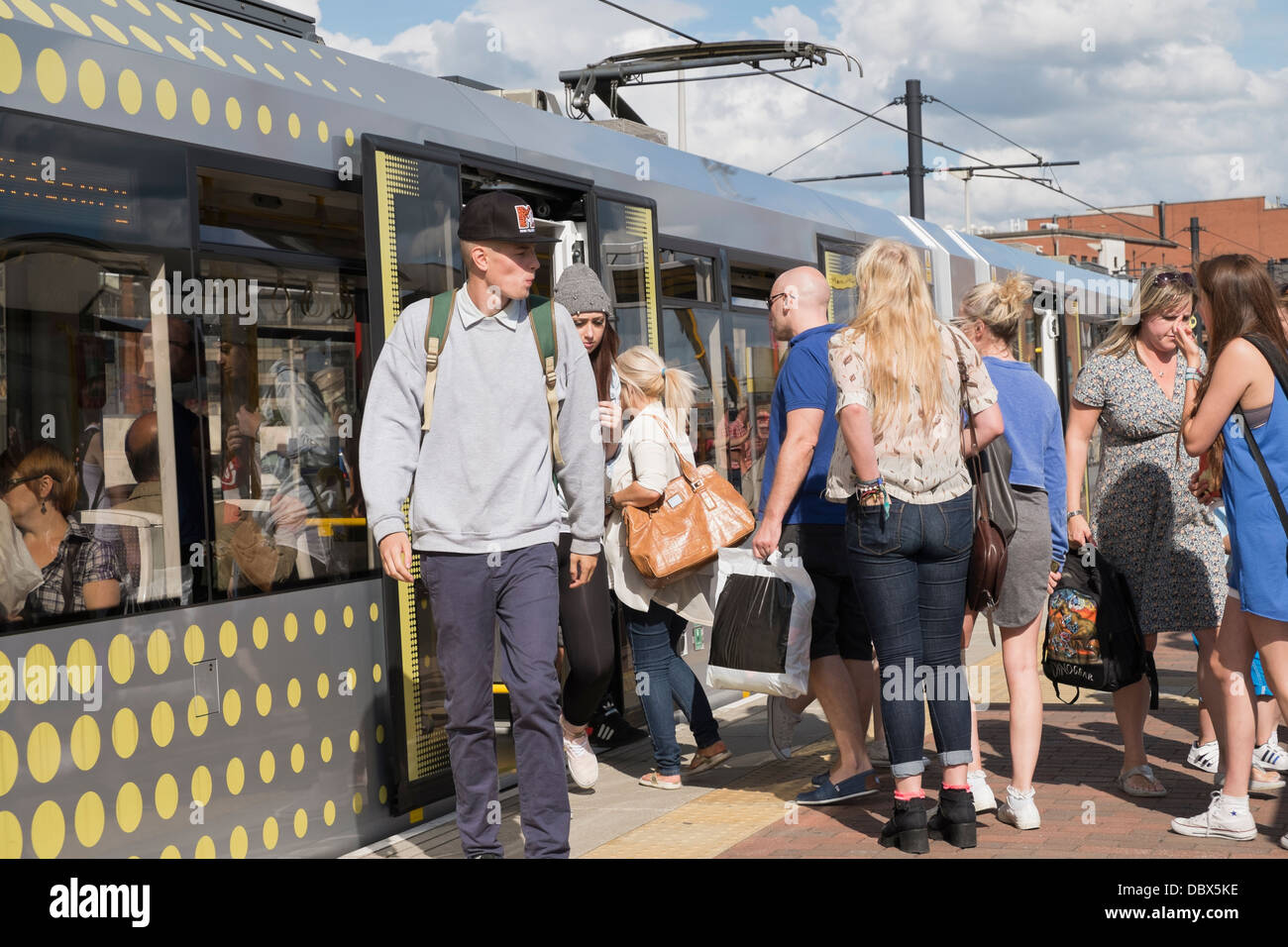 Alltägliche Szene der Passagiere auf überfüllten Plattform mit Menschen an Bord eines Metrolink tram an Deansgate-Castlefield Bahnhof in Manchester City. England Großbritannien Stockfoto