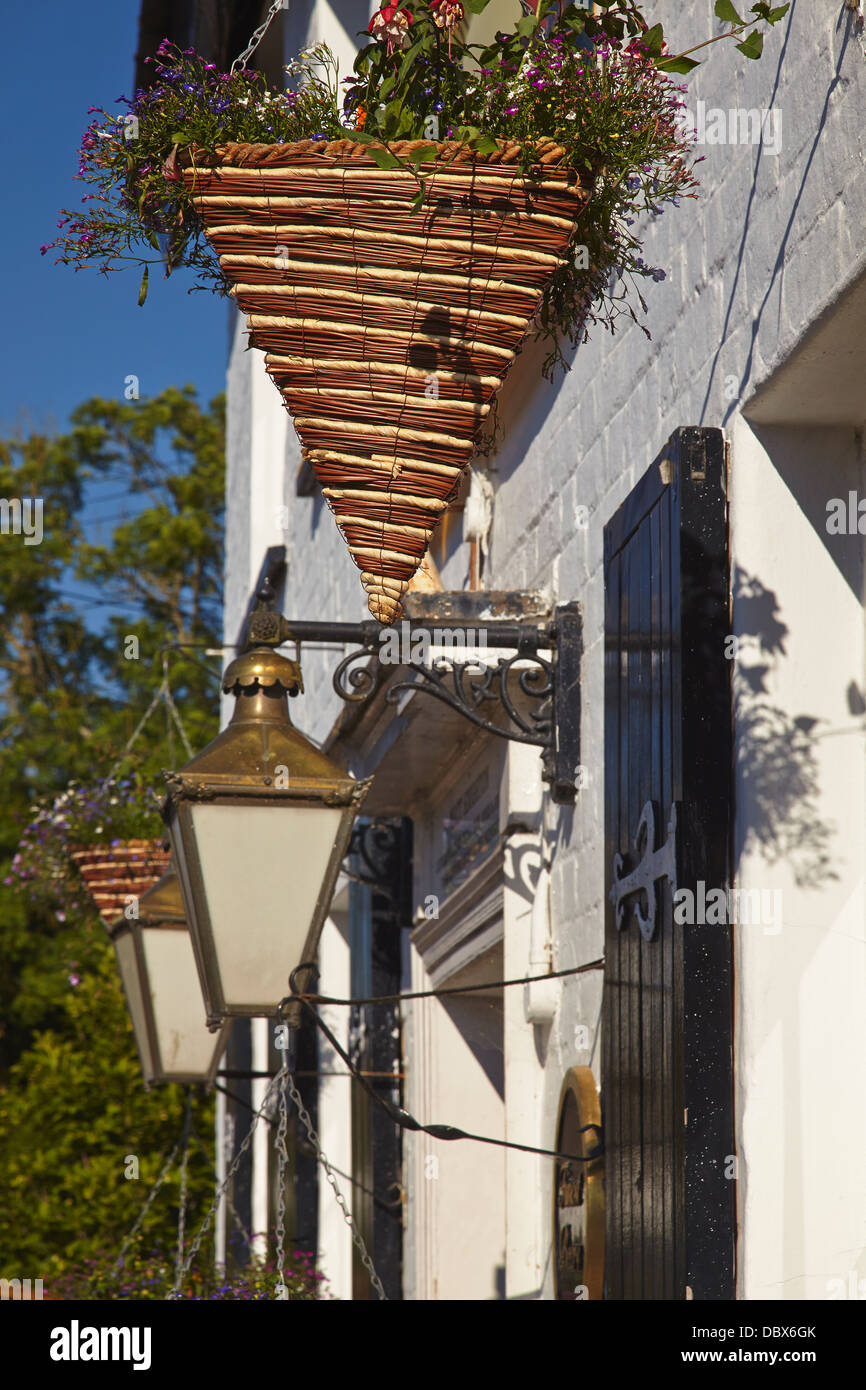 Hängekörbe und Laternen vor einem Dorfkneipe in Woodbury, nahe Exeter, Devon, Großbritannien. Stockfoto