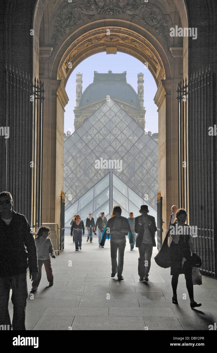 Besucher nähern und Abfahrt durch einen Torbogen im Louvre Museum in Paris, Frankreich.  Hinter ist die Glaspyramide Stockfoto