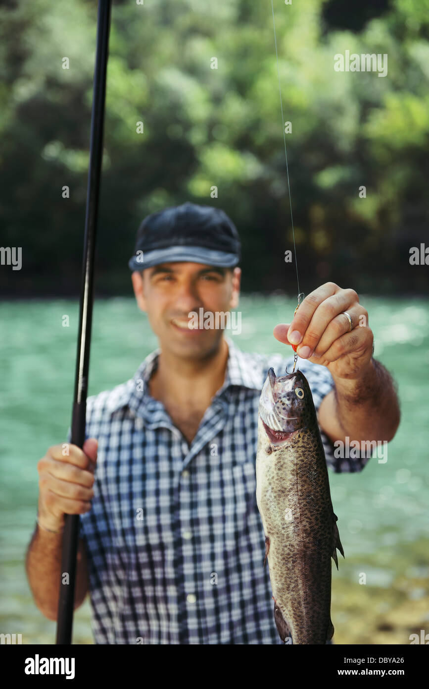 Mitte Erwachsene Fischer an Feiertagen am Fluss, entspannen und Forellen angeln. Fisch im Fokus Stockfoto