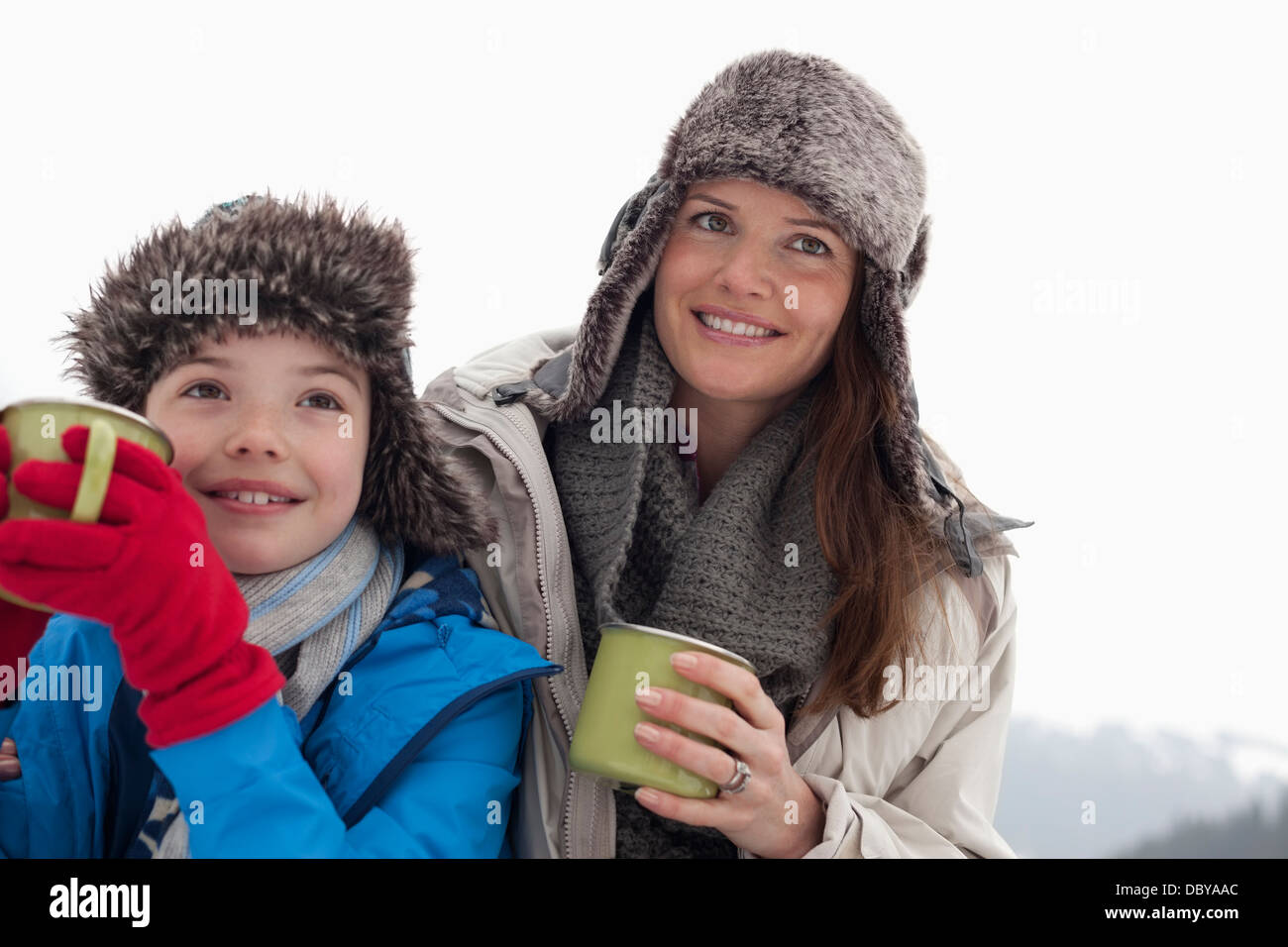 Glückliche Mutter und Sohn in Pelzmützen trinken heiße Schokolade Stockfoto