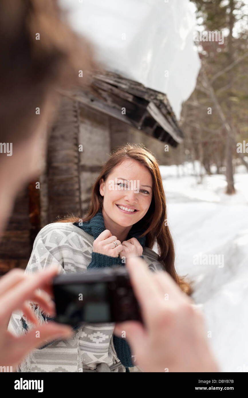Mann fotografiert lächelnde Frau im Schnee Außenkabine Stockfoto