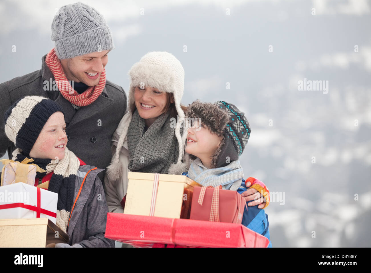 Glückliche Familie tragen Weihnachtsgeschenke im Schnee Stockfoto