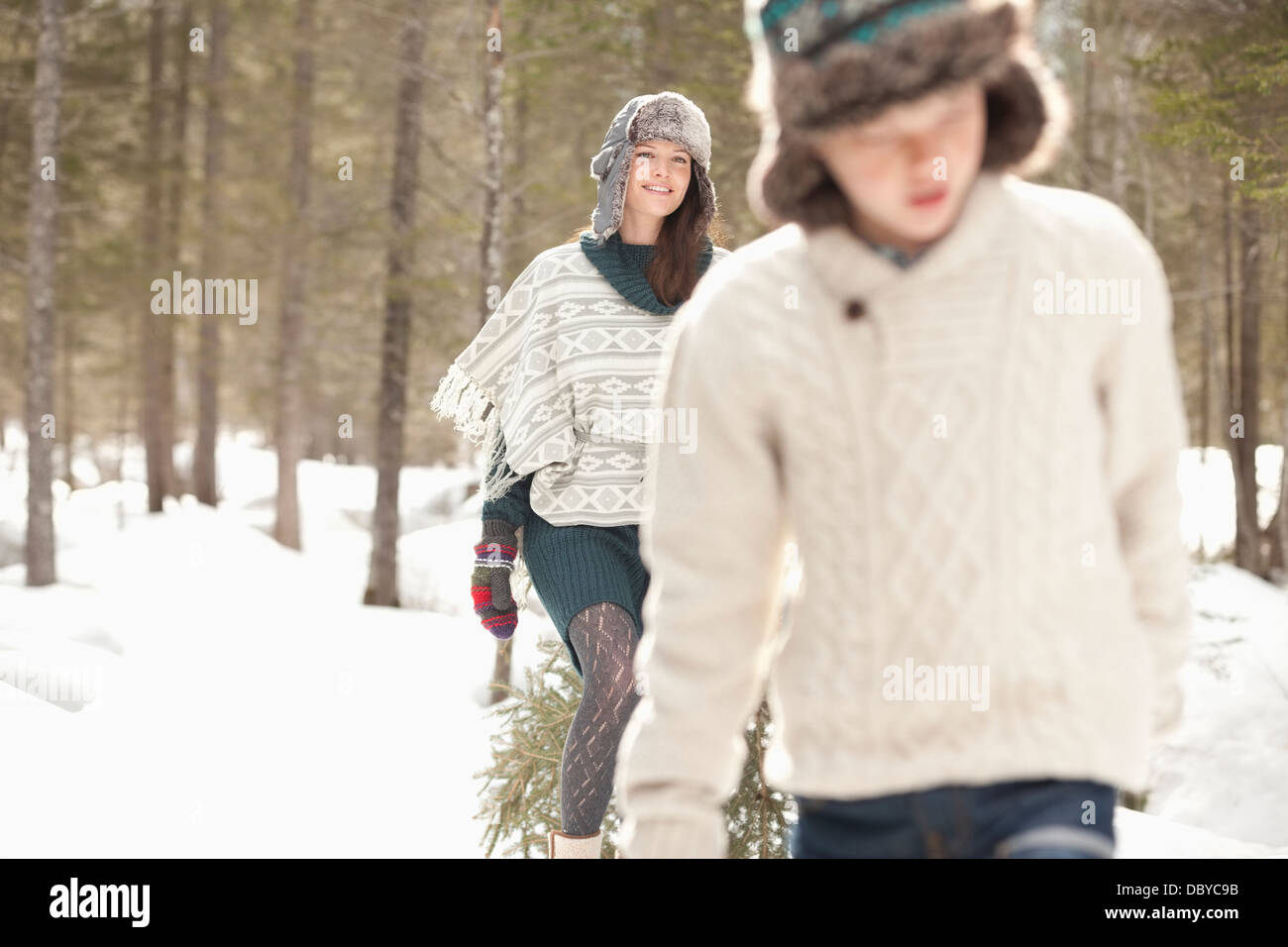 Mutter und Sohn ziehen frischen Weihnachtsbaum im verschneiten Wald Stockfoto