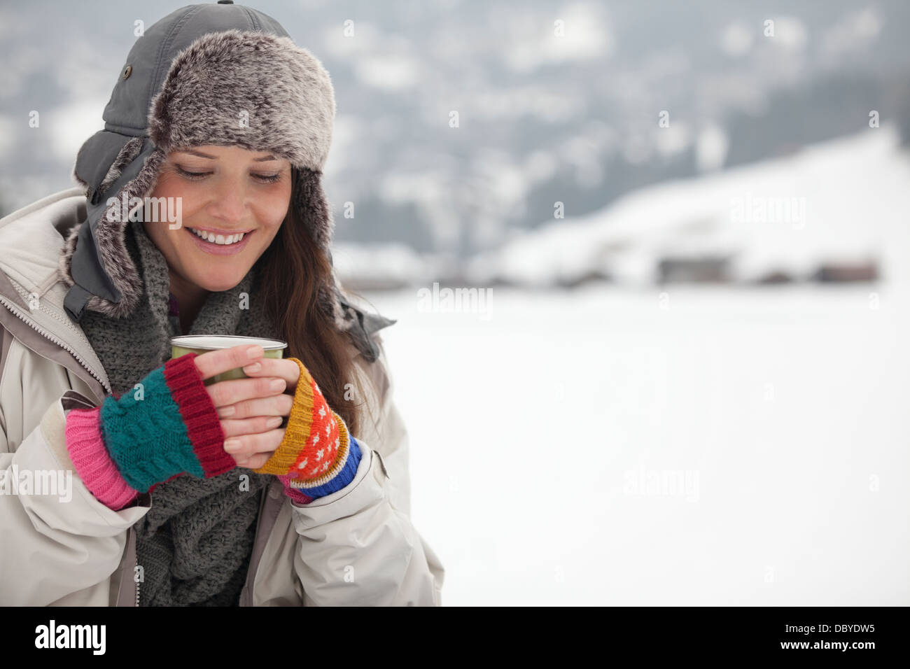 Lächelnde Frau Kaffee trinken im Schnee Stockfoto
