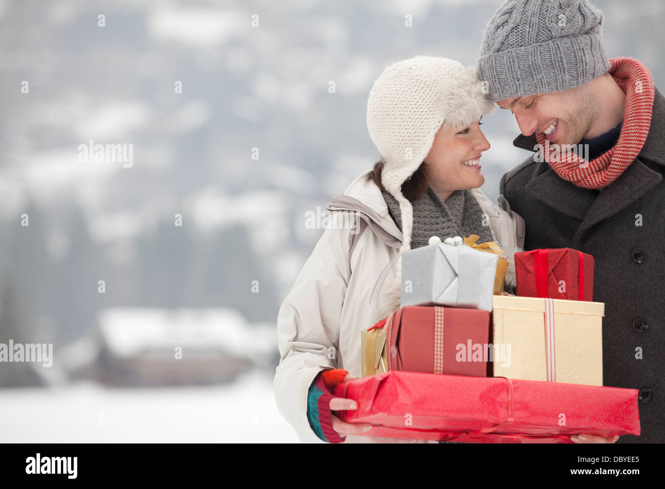 Glückliches Paar tragen Weihnachtsgeschenke im Schnee Stockfoto