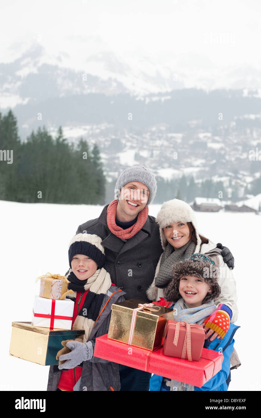 Porträt der glückliche Familie Weihnachtsgeschenke in schneebedeckten Feld tragen Stockfoto