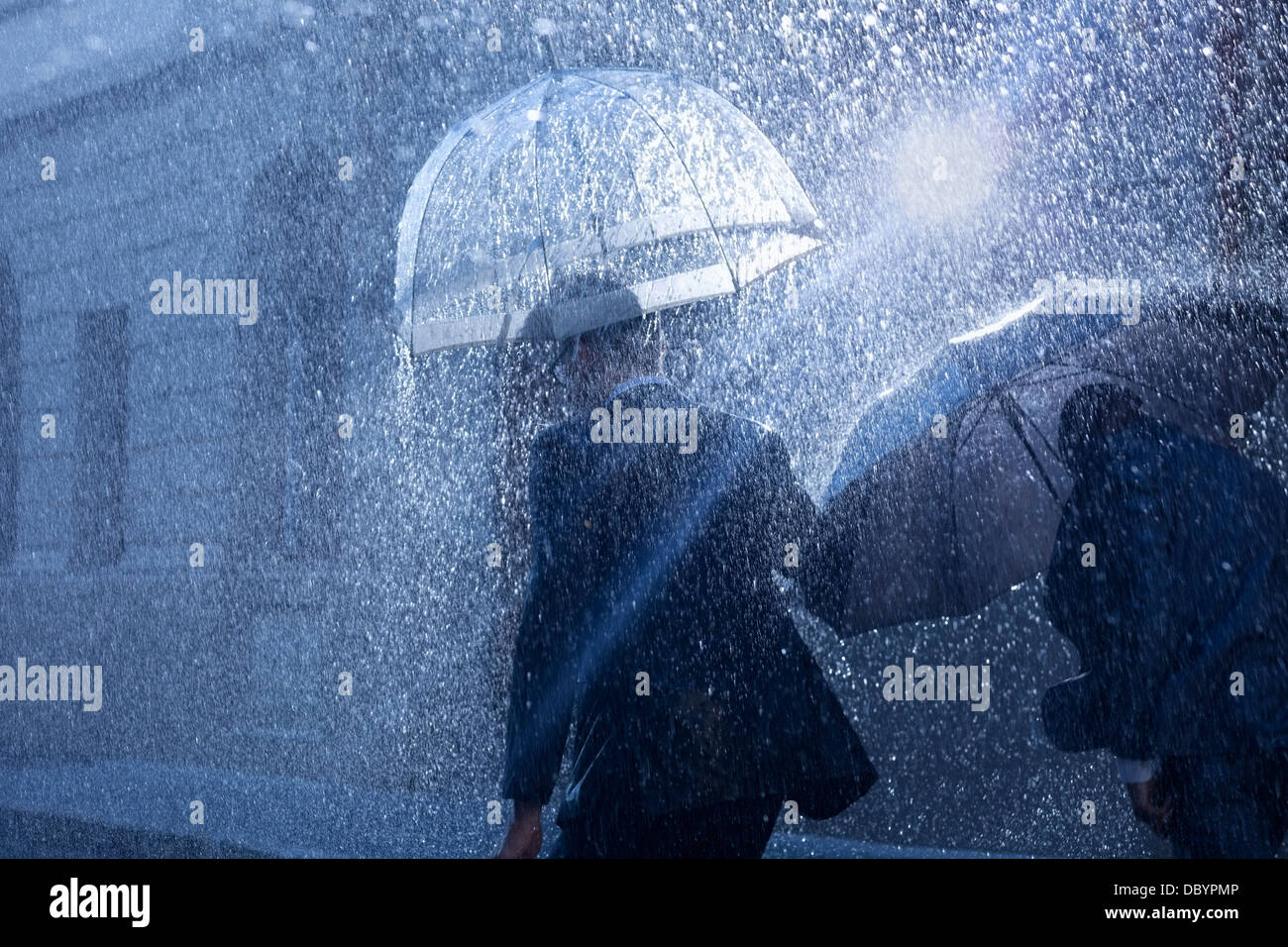 Geschäftsleute mit Sonnenschirmen im Regen Stockfoto