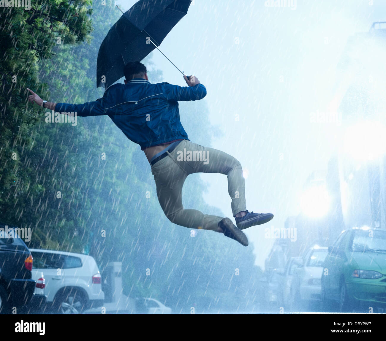 Mann mit Schirm im Regen springen Stockfoto