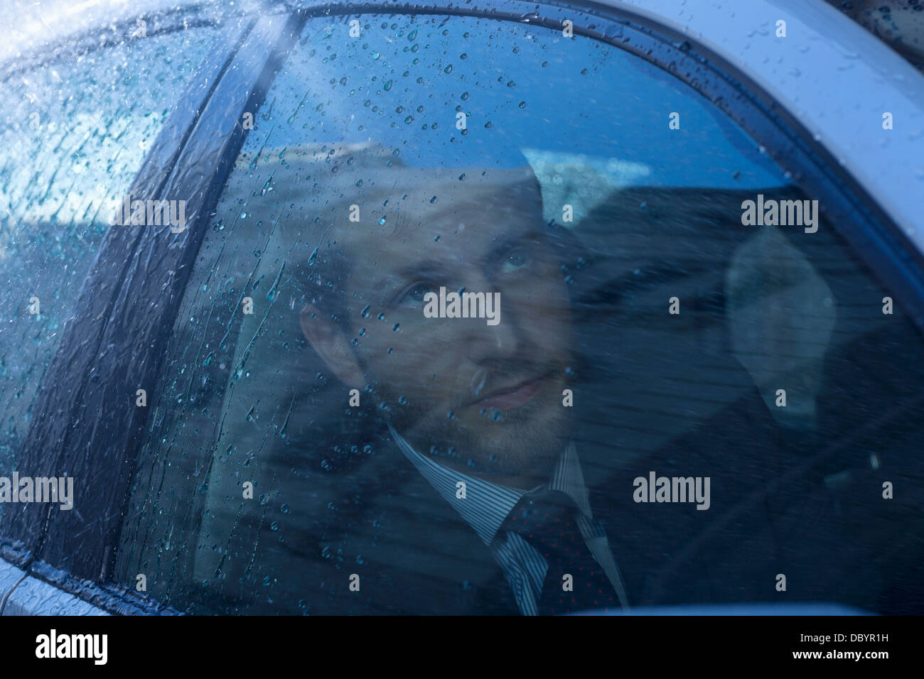 Nahaufnahme von Geschäftsmann in Auto blickte zu Regen Stockfoto
