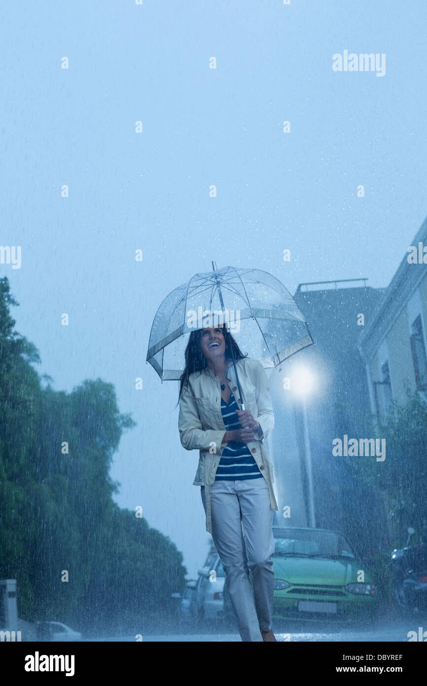 Glückliche Frau mit Regenschirm Wandern in Regen Stockfoto