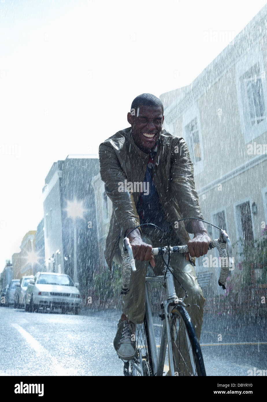Glücklich Kaufmann Reiten Fahrrad im Regen Stockfoto