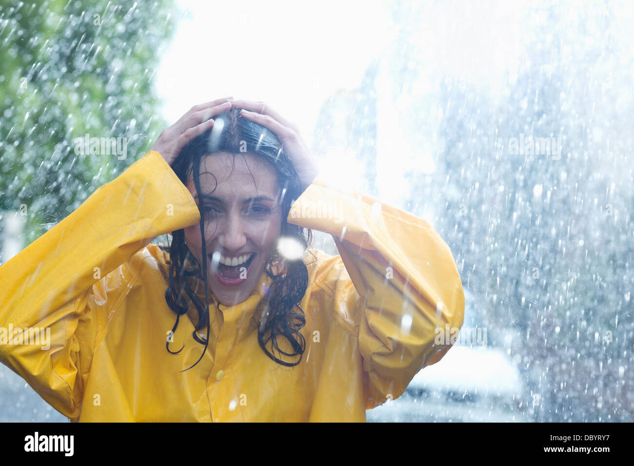 Glückliche Frau mit Händen auf Kopf im Regen Stockfoto