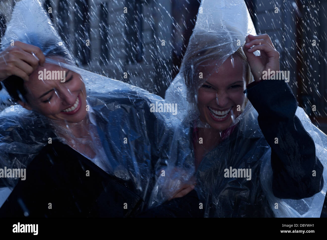 Lachend Geschäftsfrauen tragen Ponchos in Regen Stockfoto