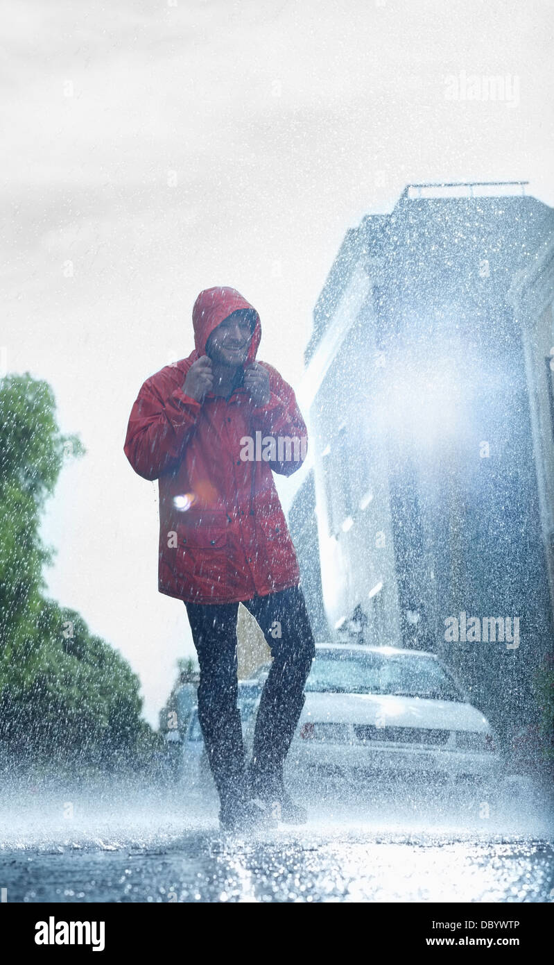 Mann im Regenmantel auf verregnete Straße Stockfoto
