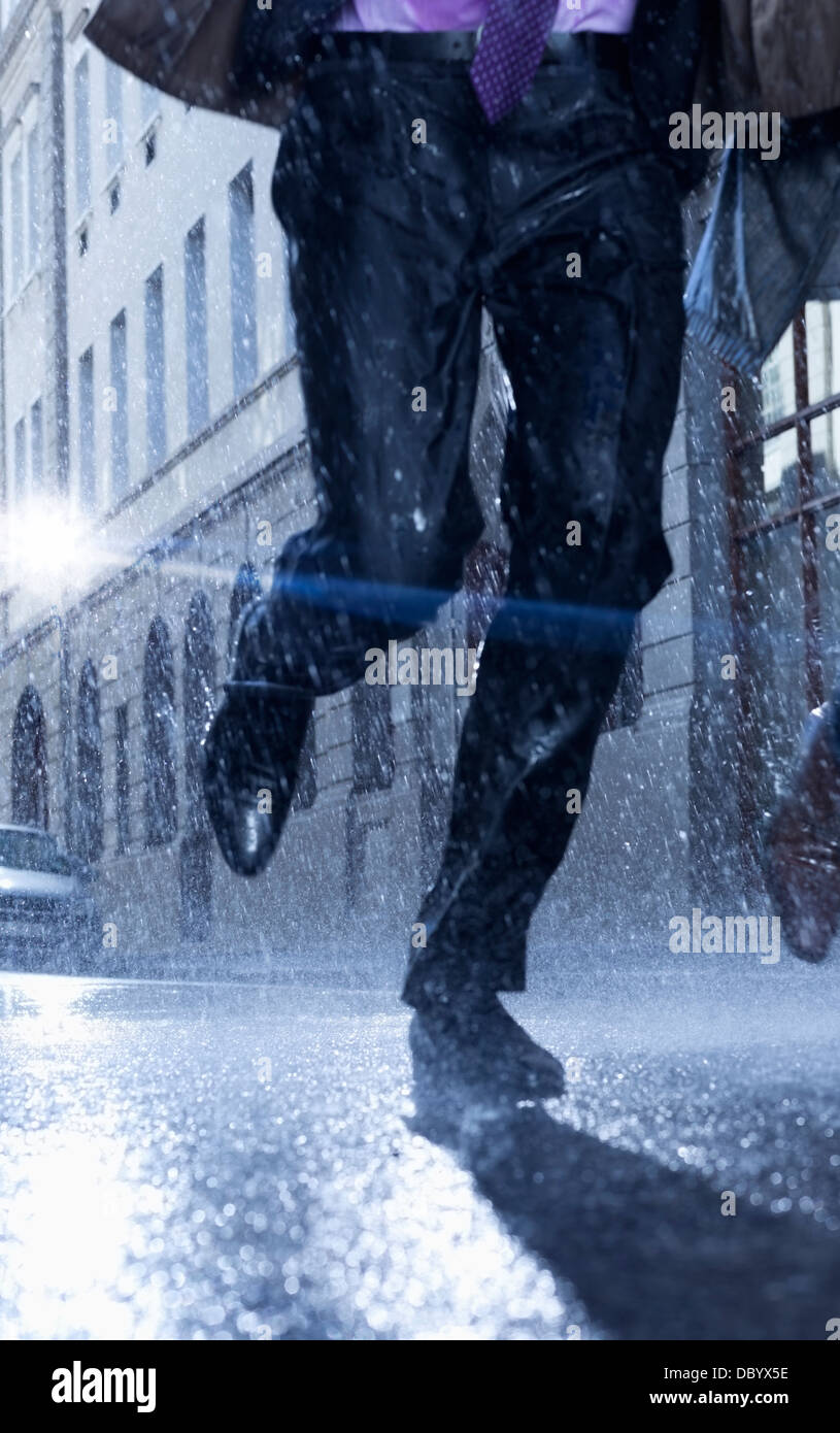 Geschäftsmann im verregneten Straße laufen Stockfoto