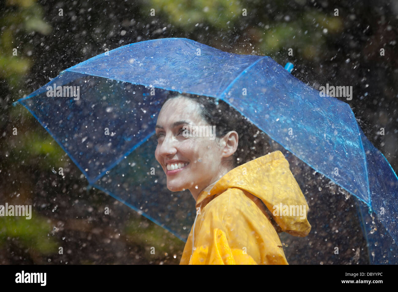 Glückliche Frau mit Regenschirm im Regen Stockfoto
