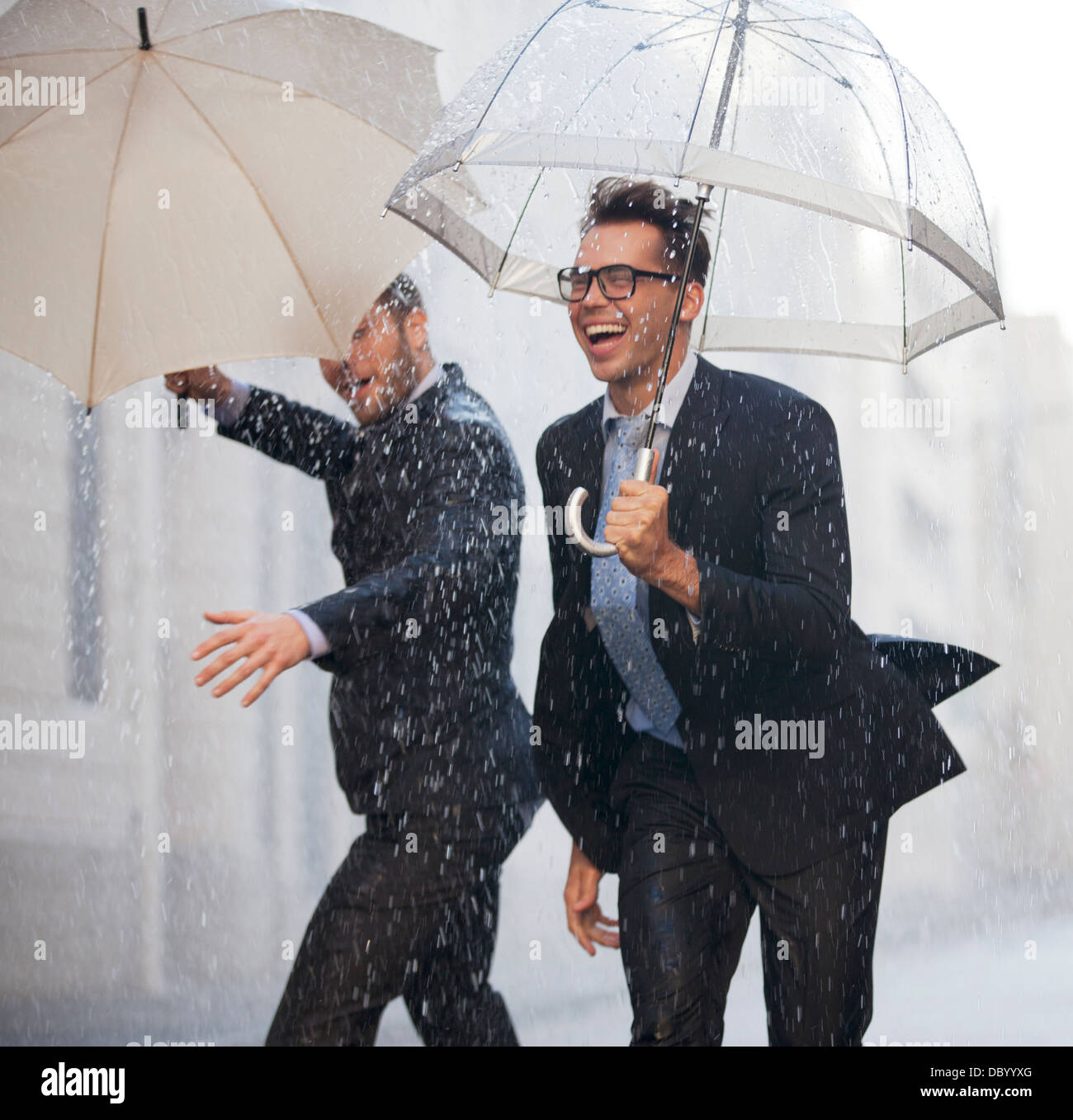 Glücklich Geschäftsleute mit Regenschirmen Wandern in Regen Stockfoto