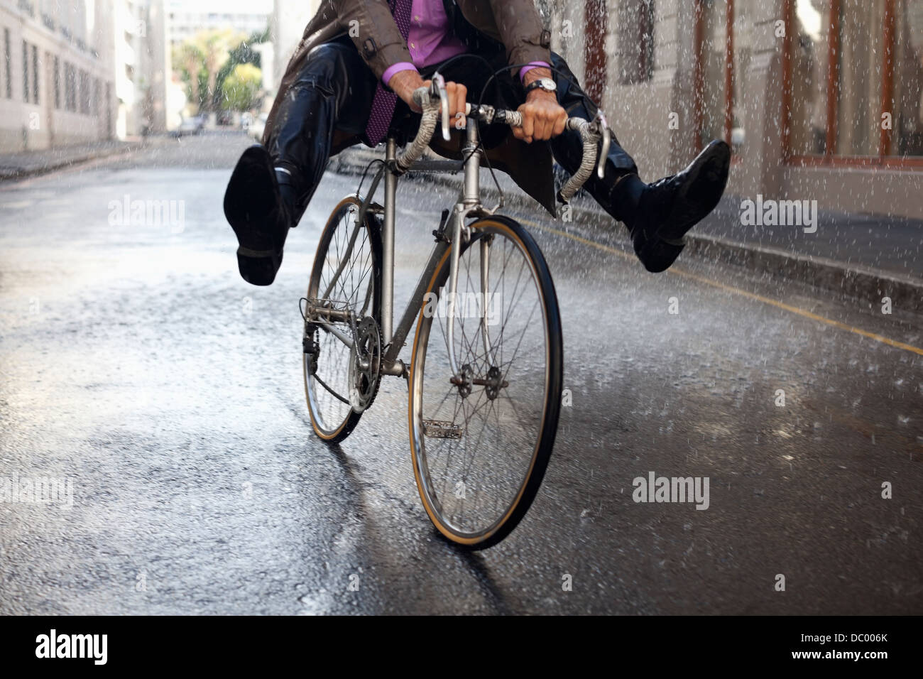 Geschäftsmann, Fahrrad mit Füßen in Regen Stockfoto