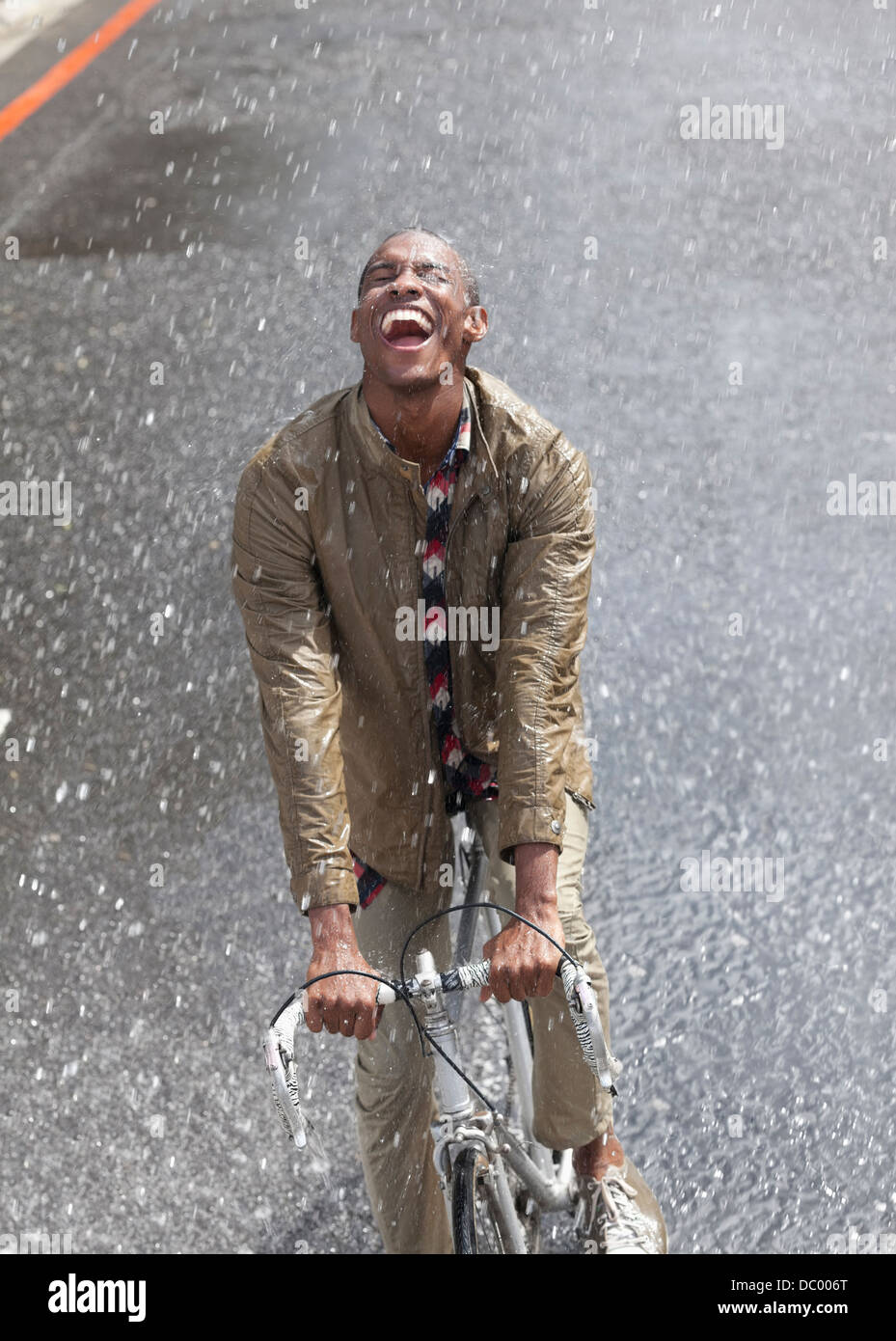 Begeisterten Mann Reiten Fahrrad im Regen Stockfoto