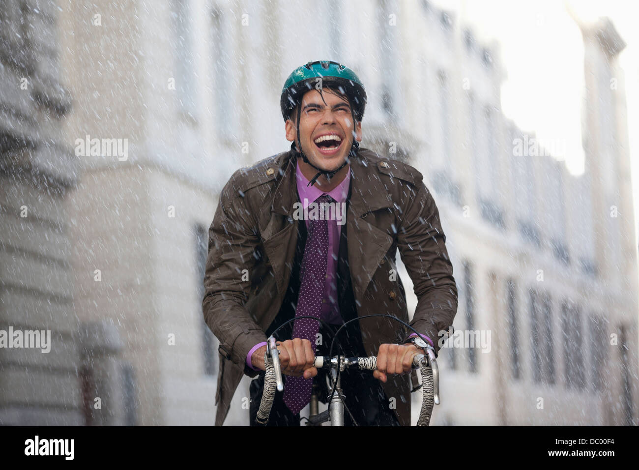 Begeisterte Unternehmer Reiten Fahrrad im Regen Stockfoto