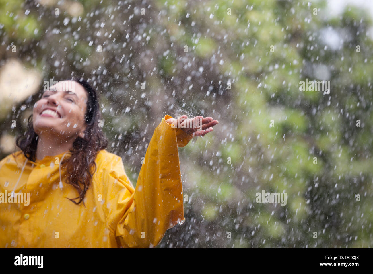 Glückliche Frau mit ausgestreckten im Regen stehen Stockfoto