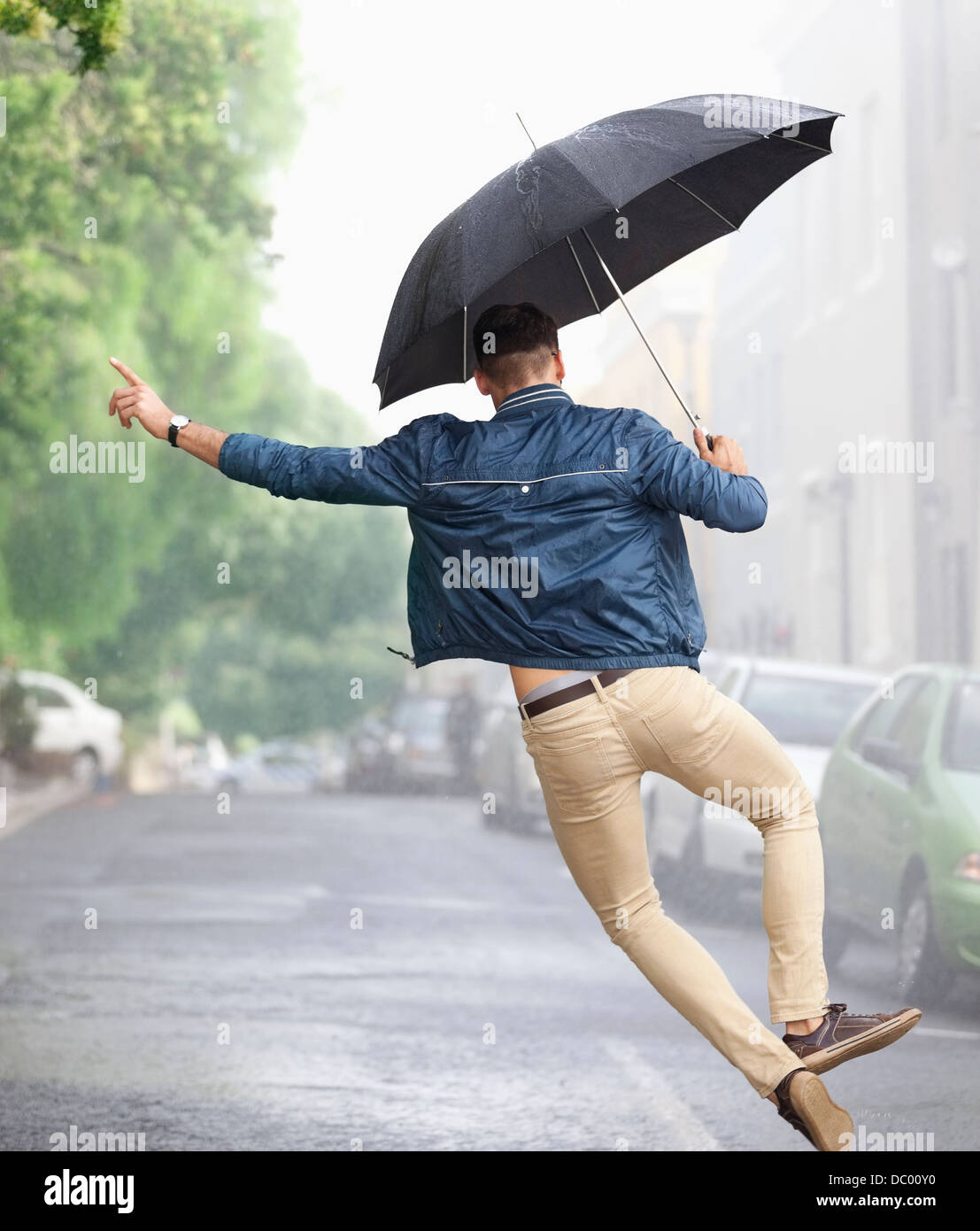 Mann mit Regenschirm im verregneten Straße tanzen Stockfoto