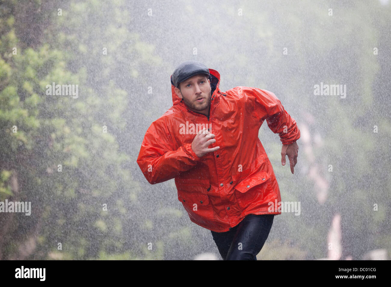 Mann im Regenmantel laufen im Regen Stockfoto